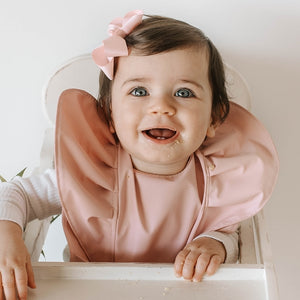 Little girl wearing waterproof pink bib and pink bow