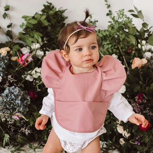 Little girl wearing a primrose pink waterproof bib and pink bow