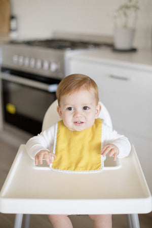 Baby wearing butterscotch linen bib