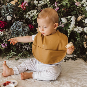 Baby boy wearing a tan coloured food bib