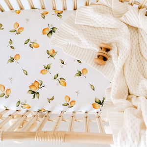Lemon print bassinet sheet and cream knit blanket in rattan bassinet