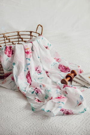 White, pink and green swaddle draped over basket