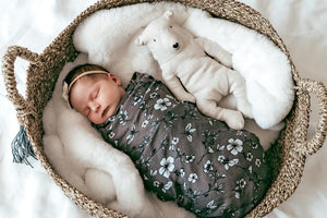 Baby wrapped in green and white floral muslin swaddle