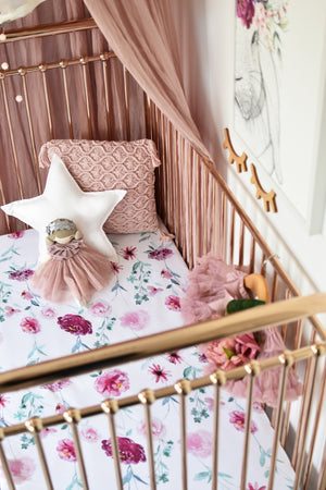 white and pink floral fitted cot sheet on gold cot 