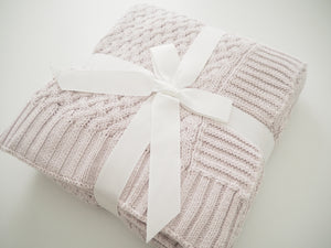 grey knit blanket folded up with a white ribbon wrapped around it